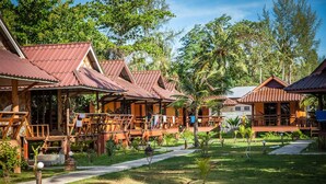 Um resort com várias cabanas de madeira, cada uma com telhado de cerâmica e rodeada por vegetação exuberante.