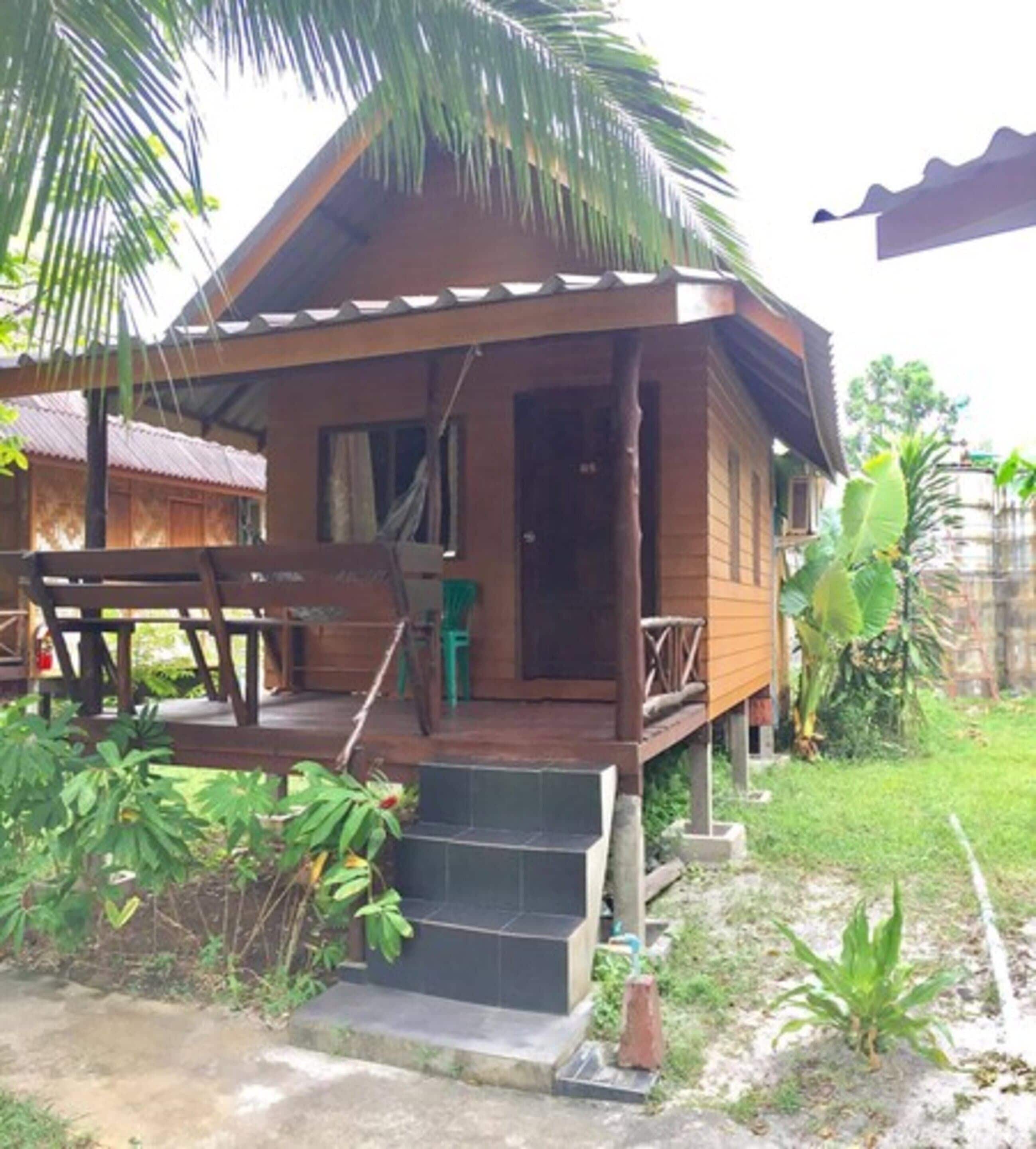 A wooden house with a porch, steps, and a small garden area.