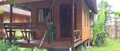 A wooden house with a porch, steps, and a small garden area.