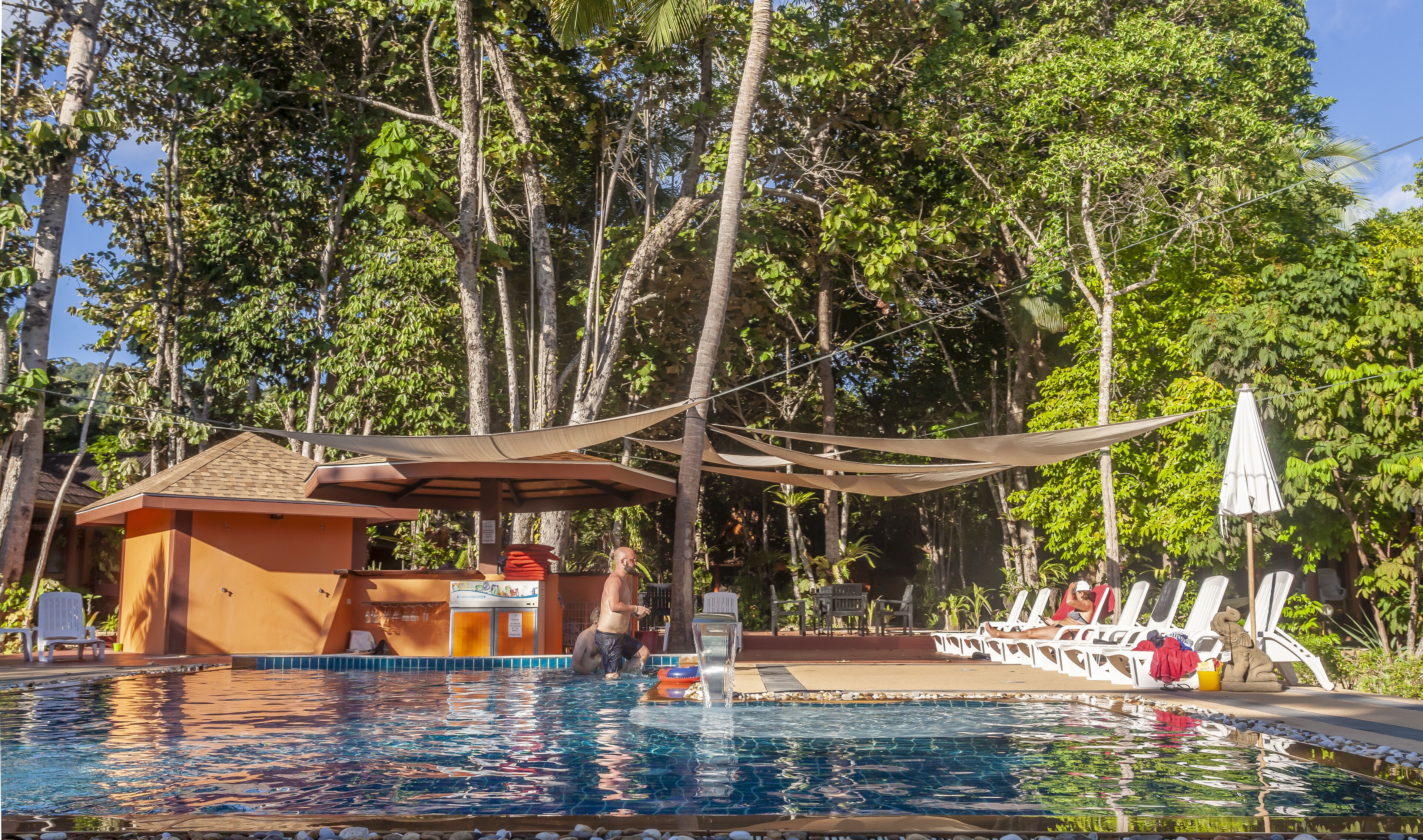A swimming pool with lounge chairs and a shaded area.