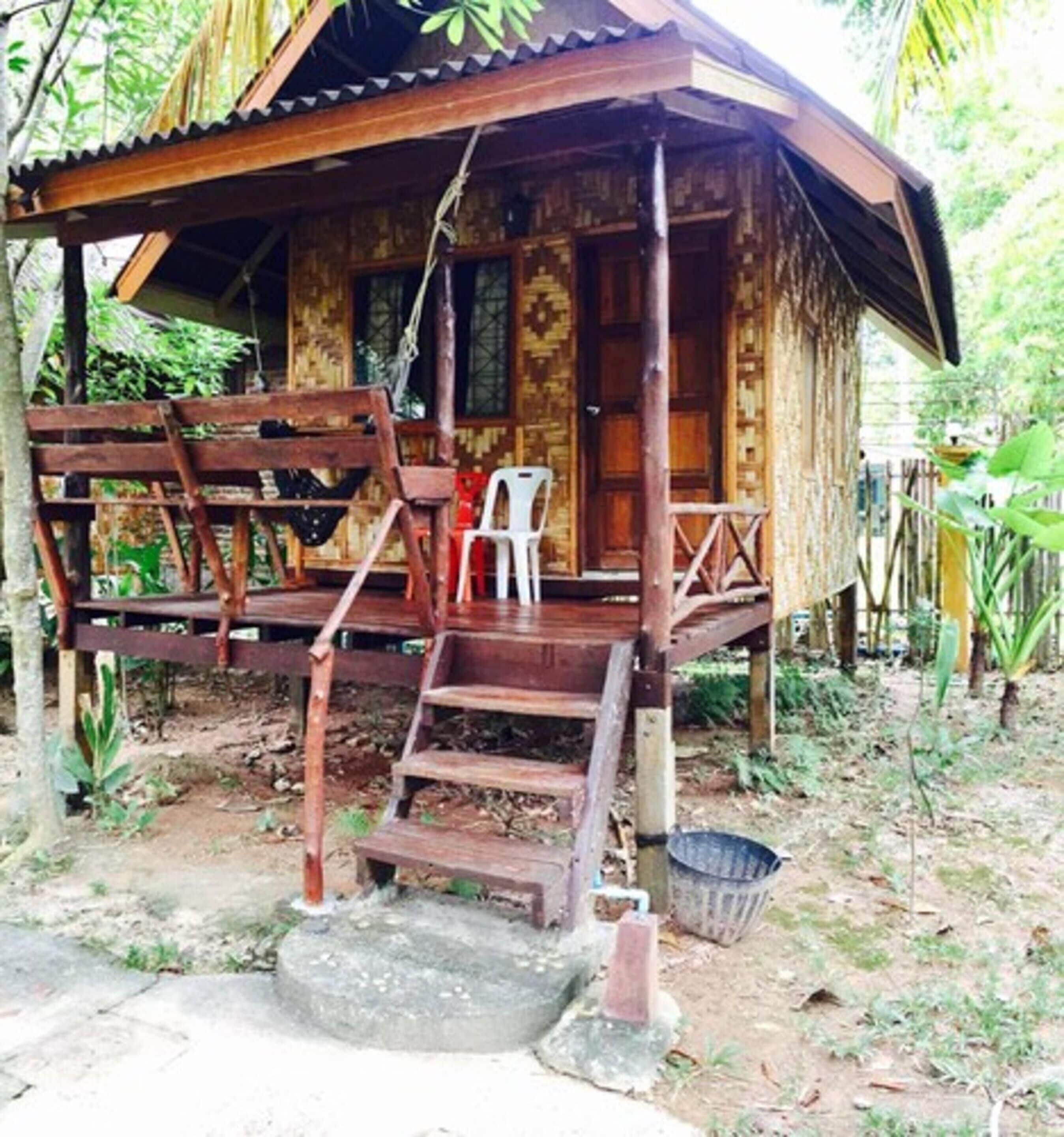 A wooden house with a porch, steps leading to the entrance, and a small outdoor seating area.