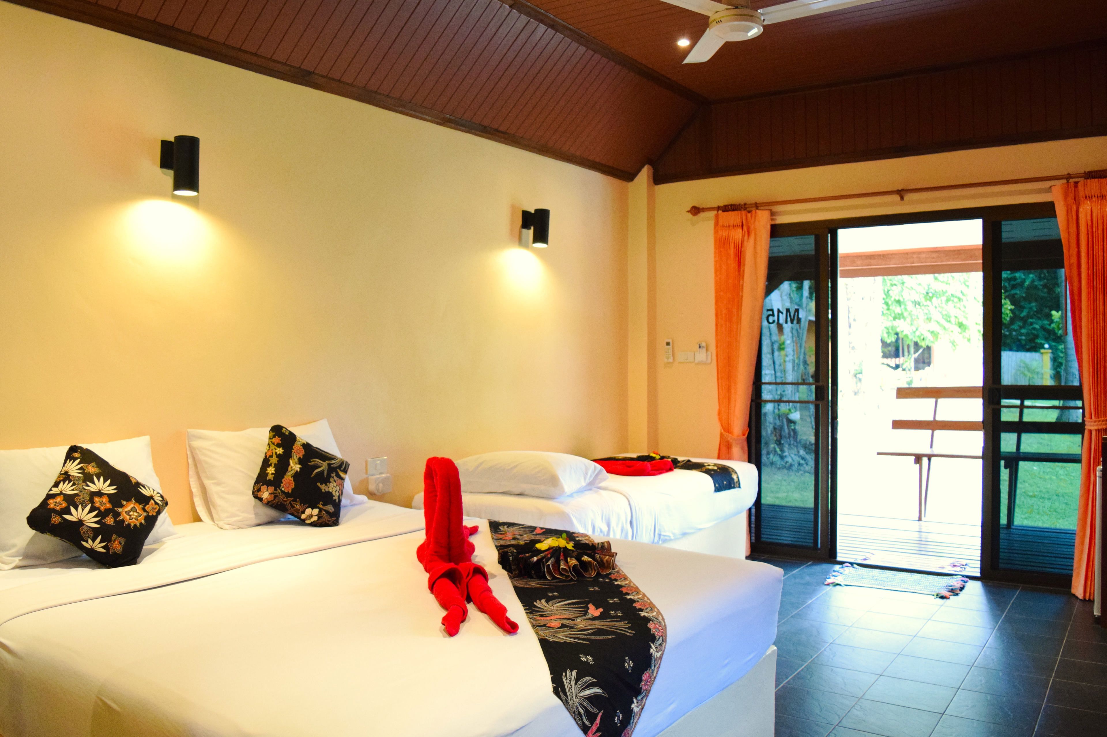 A hotel room with two beds, a red towel, and a view of the outdoors.