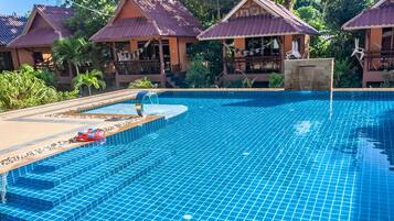 Een buitenzwembad, ligstoelen bij het zwembad