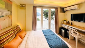 A hotel room with a bed, a desk, a TV, and a view of the outdoors.