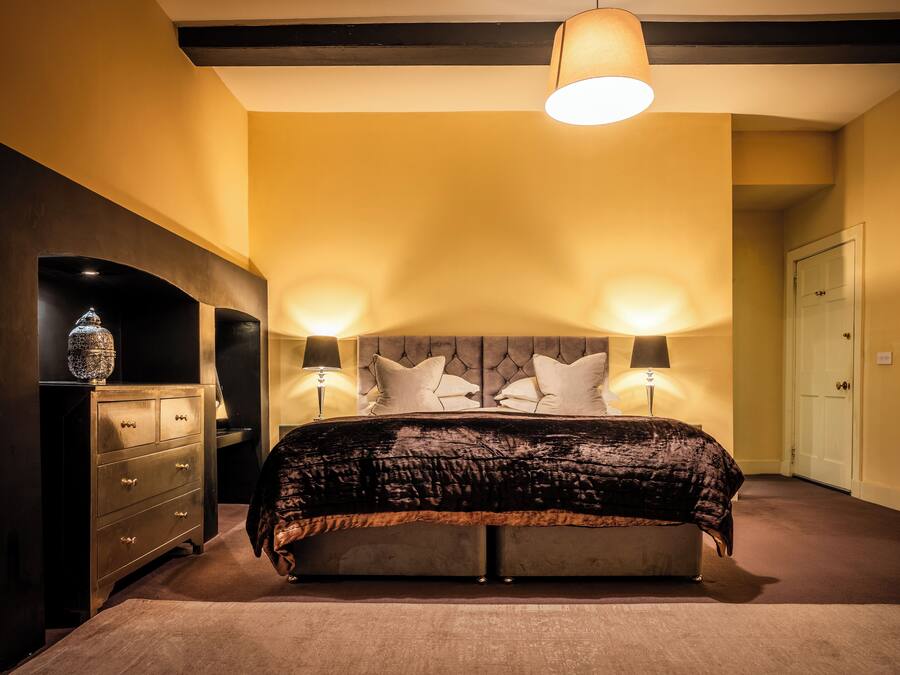Une chambre à coucher avec un grand lit, deux lampes de chevet, une commode et une porte.