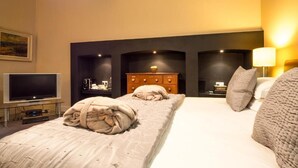 A hotel room with a large bed, a flat-screen TV, a wooden dresser, and a wall-mounted shelf. - Six Brunton Place (Edinburgh)
