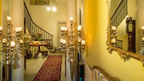 A grand staircase with a mirror, candle sconces, and a patterned carpet leading to a room with a painting on the wall. - Six Brunton Place (Edinburgh)