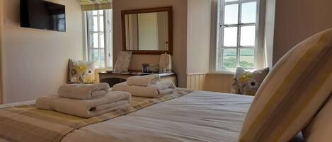 Habitación de hotel con cama, escritorio, televisor de pantalla plana y ventana con vista al campo.