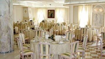 Un comedor formal con varias mesas redondas, cada una dispuesta con sillas y vajilla.