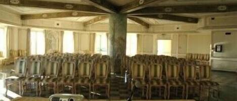 Un salón amplio con filas de sillas y una zona escenario.