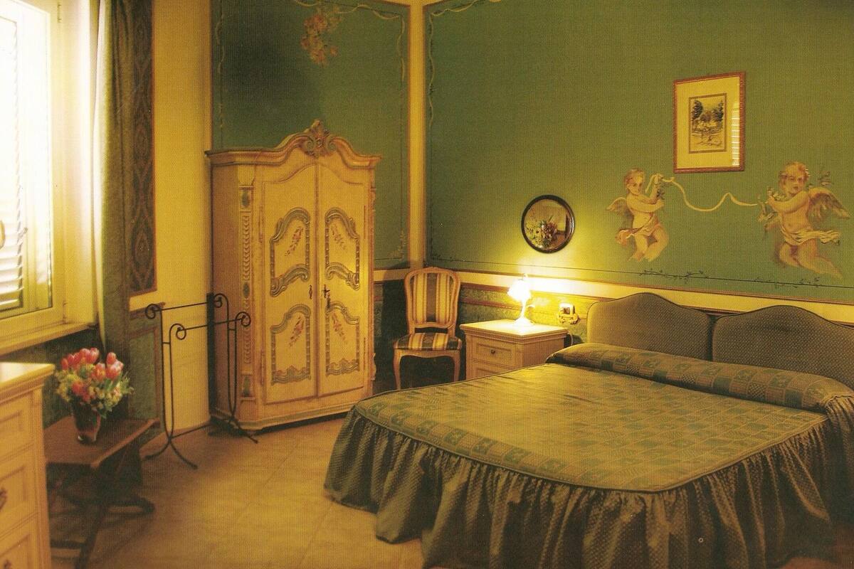 A room with a bed, a dresser, a chair, and a nightstand with a lamp.