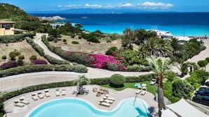 Un complexe hôtelier doté d’une piscine, de chaises longues et offrant une vue sur la mer.