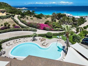 Un resort con piscina, sillones de descanso y vistas al mar.