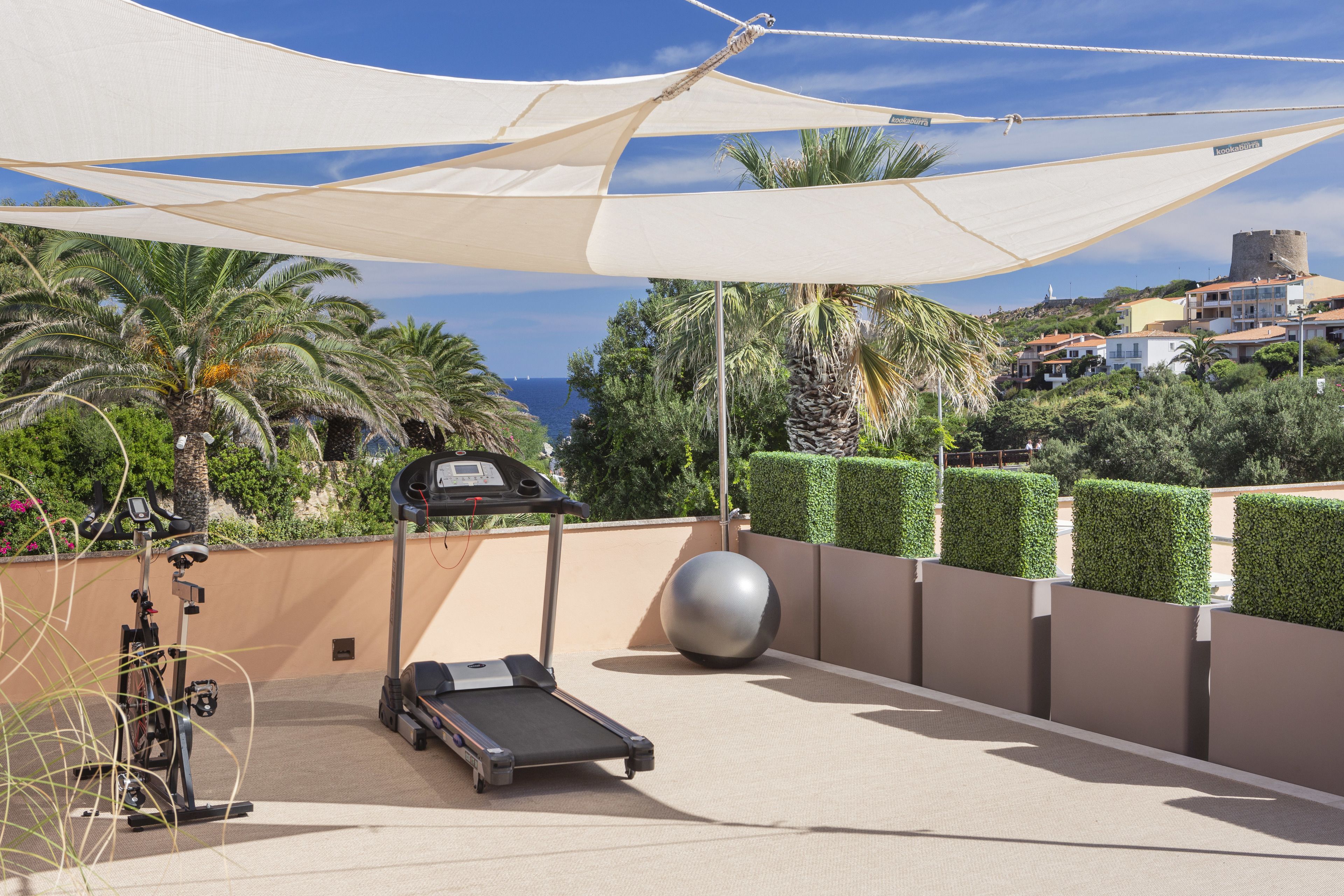 Terraza en la azotea con equipo de ejercicio, una pelota grande y vistas al mar y edificios.