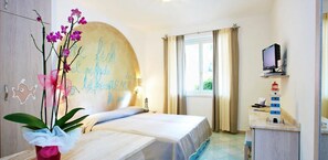Hotelkamer met een bed, een bureau met computer, een raam met gordijnen en een decoratieve wand met tekst.