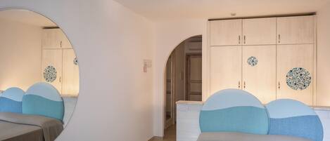 Ein Schlafzimmer mit einer Spiegelwand, einem Schrank mit dekorativen Tellern und einem Bett mit gemusterten Kissen.
