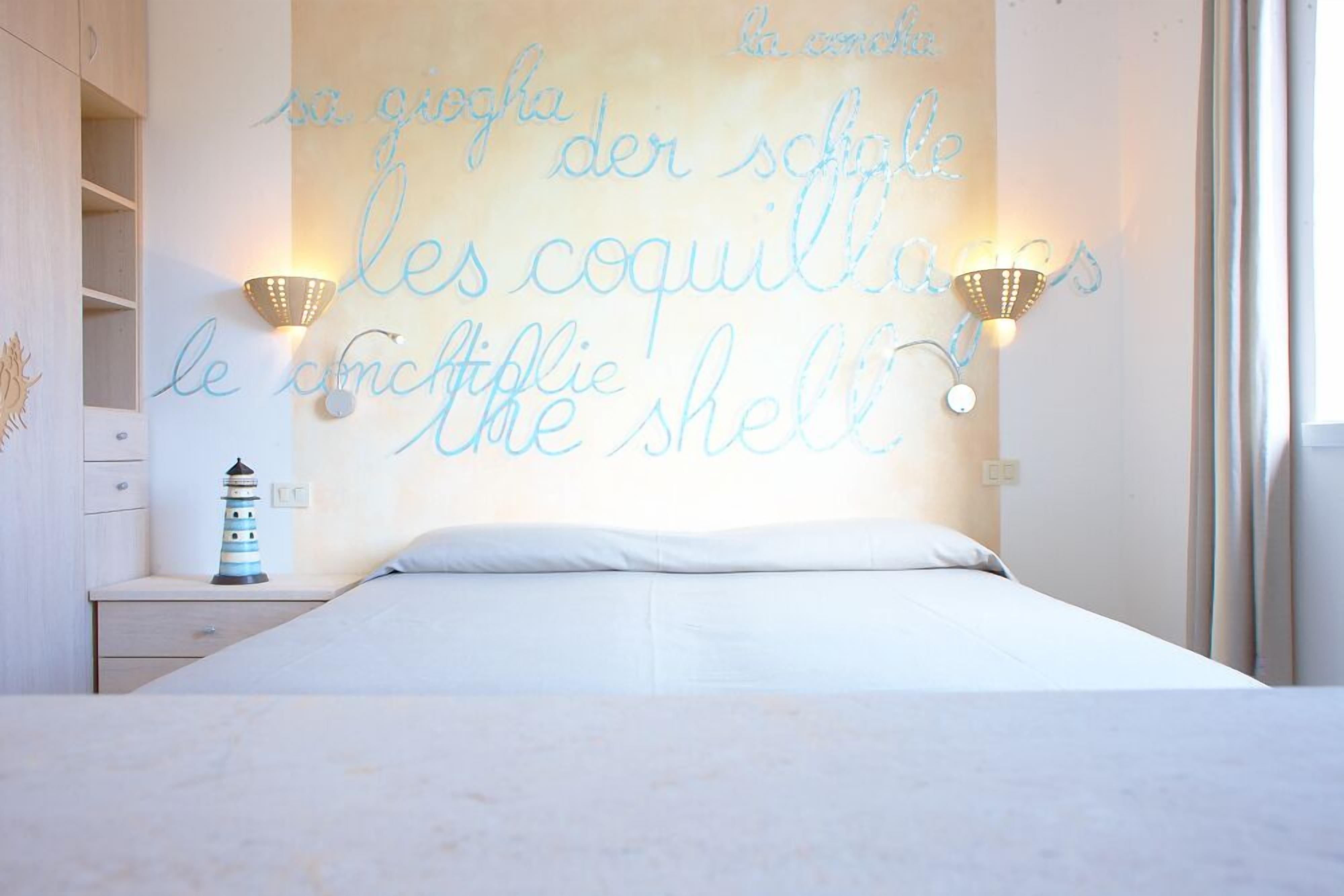 A bedroom with a bed, a nightstand, a wall-mounted light fixture, and a decorative lighthouse.