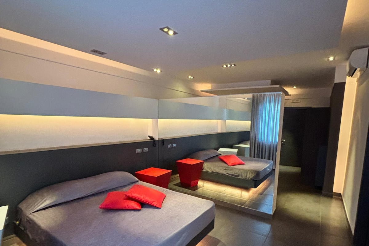 Una habitación de hotel moderna con una cama grande, una cama más pequeña y un espacio de descanso.