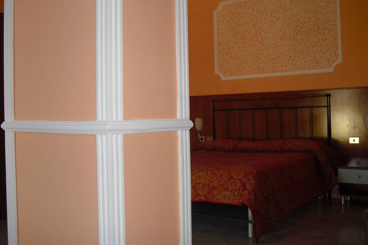 Un dormitorio con cama, una mesita de noche y una pared con diseño decorativo.
