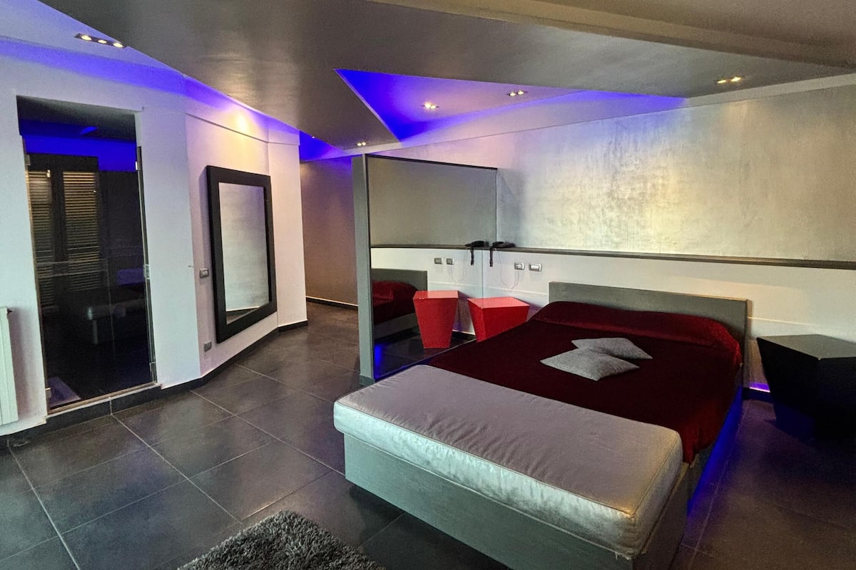 Un dormitorio moderno con una cama grande, una mesita de noche y un espejo.