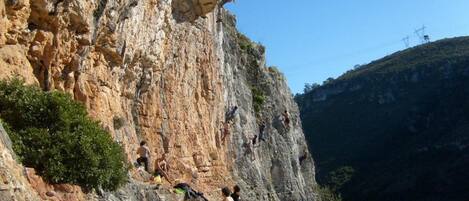 Une falaise rocheuse où l’on voit des personnes faire de l’escalade et s’asseoir sur la corniche.