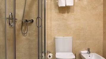 A modern bathroom with a glass-enclosed shower, a toilet, and a bidet.