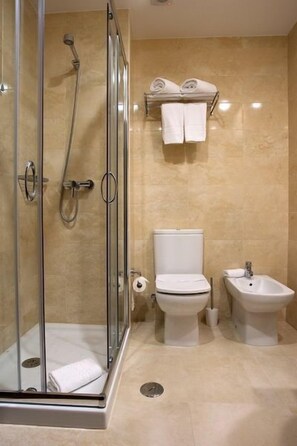 A modern bathroom with a glass-enclosed shower, a toilet, and a bidet.