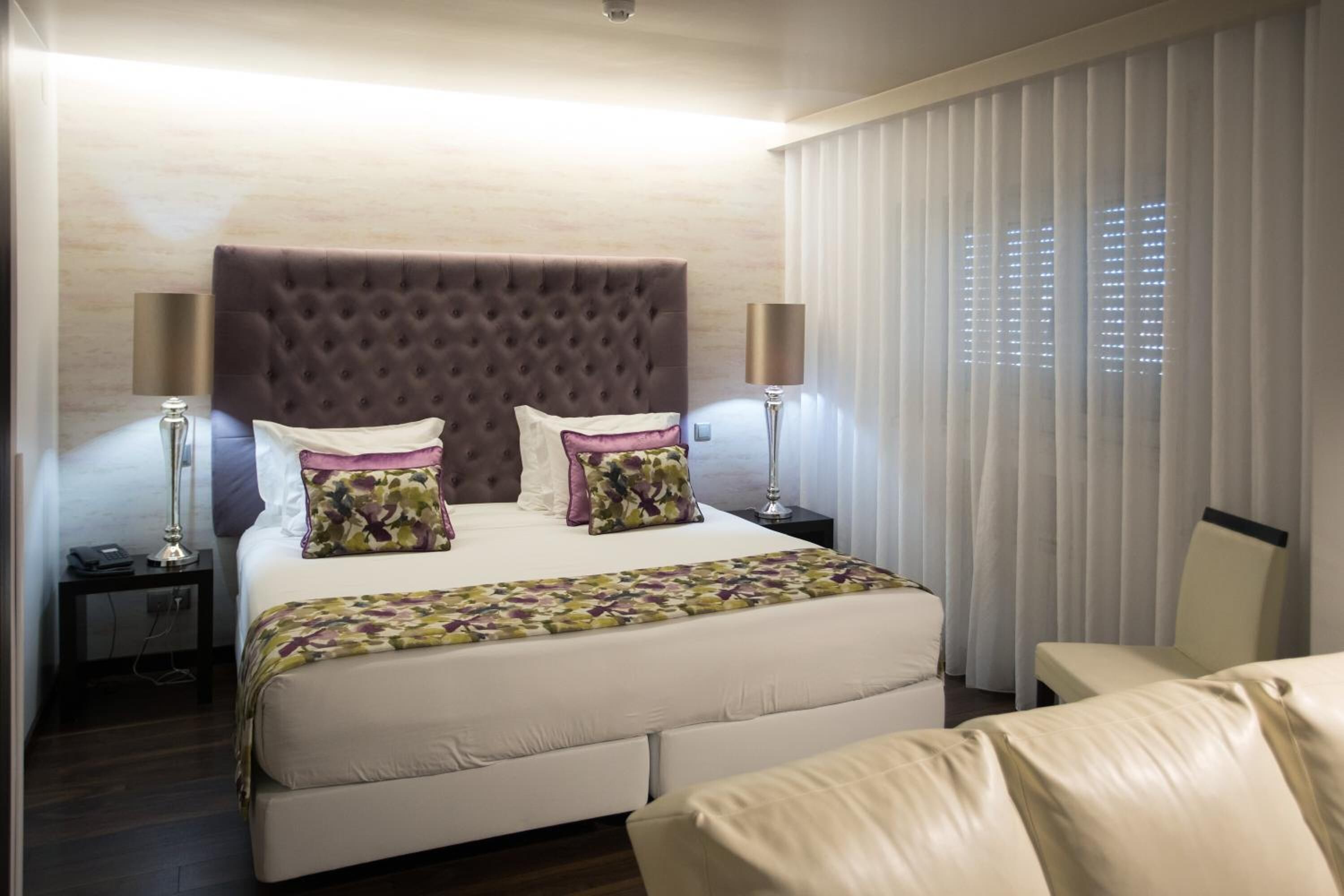 Una habitación de hotel moderna con una cama grande, dos mesitas de noche y una silla.