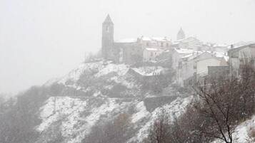 A snow-covered hill with a historic building featuring a tower, surrounded by other buildings.