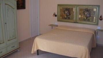 A bedroom with a bed, a wardrobe, and two framed artworks on the wall.