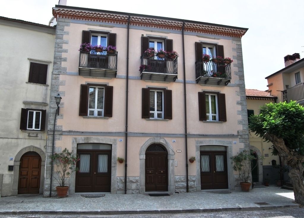 Ein zweistöckiges Gebäude mit einer Steinaußenwand, zahlreichen Fenstern mit Fensterläden und Balkonen mit Blumenkästen.