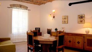 Un comedor con una mesa y sillas de madera, una ventana con cortina e iluminación en la pared.
