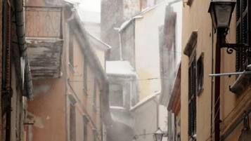 A narrow street with snow-covered buildings and a parked car.