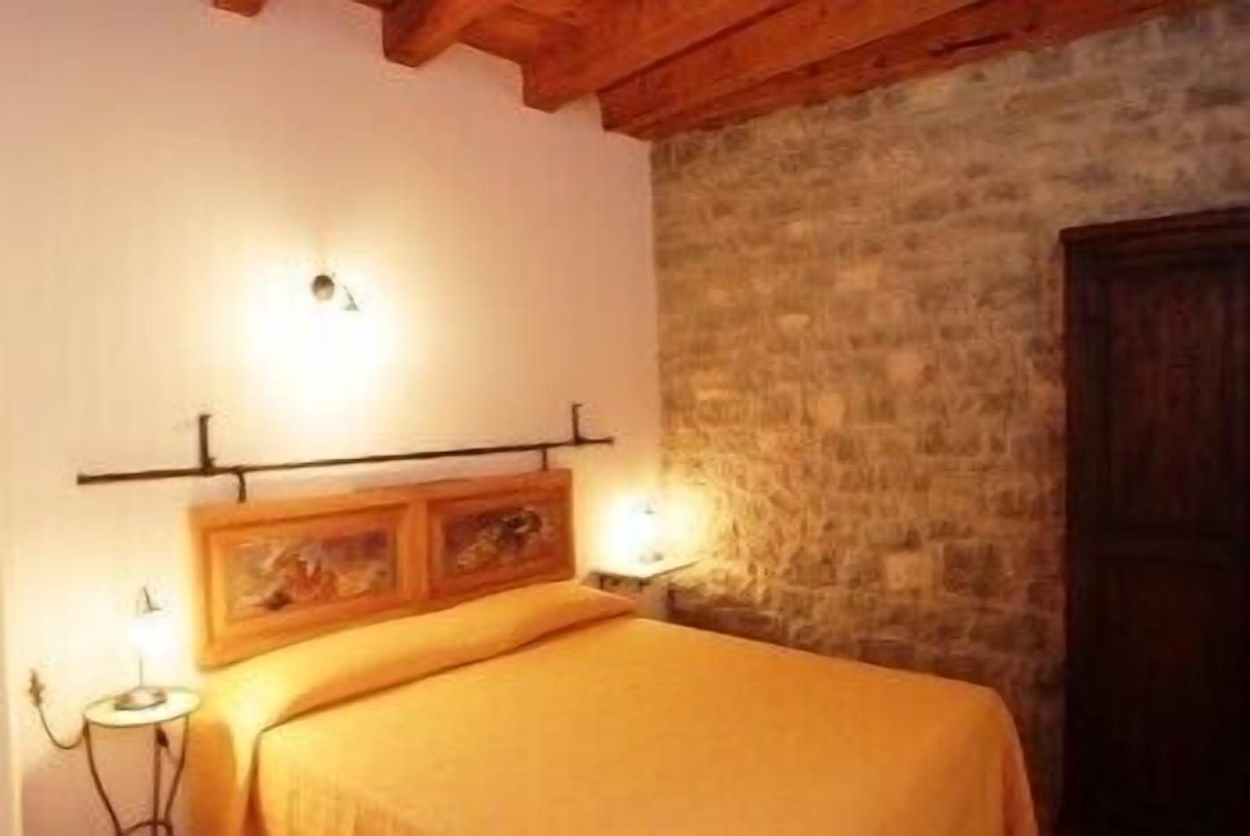 A room with a bed, a stone wall, and a wooden door.