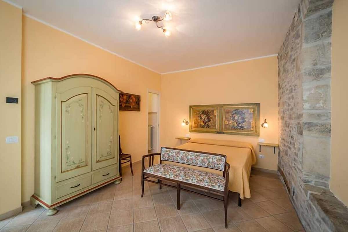 A room with a wooden bench, a green cabinet, and two wall-mounted lamps.