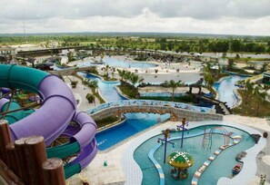 A water park with multiple pools and slides, surrounded by palm trees and a distant view of a landscape. - Labersa Grand Hotel & Convention Center (Pekanbaru)