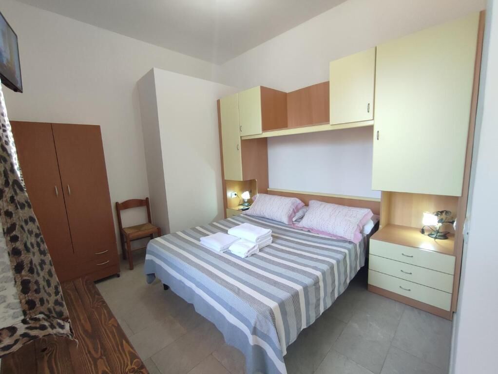 Ein Schlafzimmer mit einem Bett, Nachttischen, einem Kleiderschrank und einem Sessel.