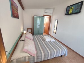 Une chambre à coucher avec un lit, une armoire, un téléviseur et un tableau accroché au mur.