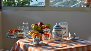 A table with breakfast items, a teapot, and a view of the sea and hills. - B&B Villa Nicoletta (Peschici)