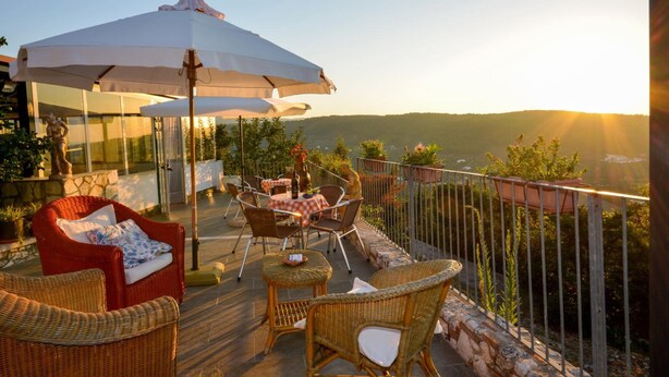 A terrace with wicker furniture, a white umbrella, and a view of the landscape. - B&B Villa Nicoletta (Peschici)