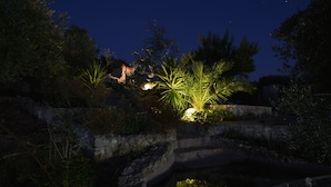 A stone bridge with a small stream underneath, surrounded by greenery and illuminated by soft lights. - B&B Villa Nicoletta (Peschici)