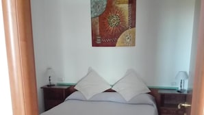 A bedroom with a bed, two nightstands, a wall art piece, and a door. - B&B Villa Nicoletta (Peschici)