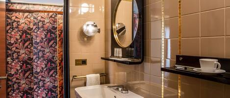 A modern bathroom with a white sink, a mirror, and a shelf with toiletries.