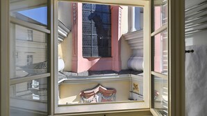 A room with a large window, a balcony, and a view of another building. - Hotel U Schnellu (Prague)