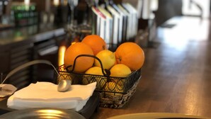 A bar area with a basket of oranges and lemons, a bottle of wine, and a candle on the counter. - Hotel U Schnellu (Prague)