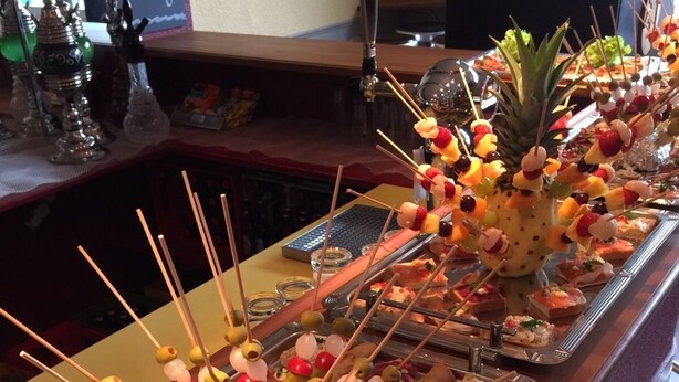 A buffet table with various food items including skewers, sandwiches, and rolls.