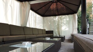 A covered outdoor seating area with wicker furniture and a glass-top table.