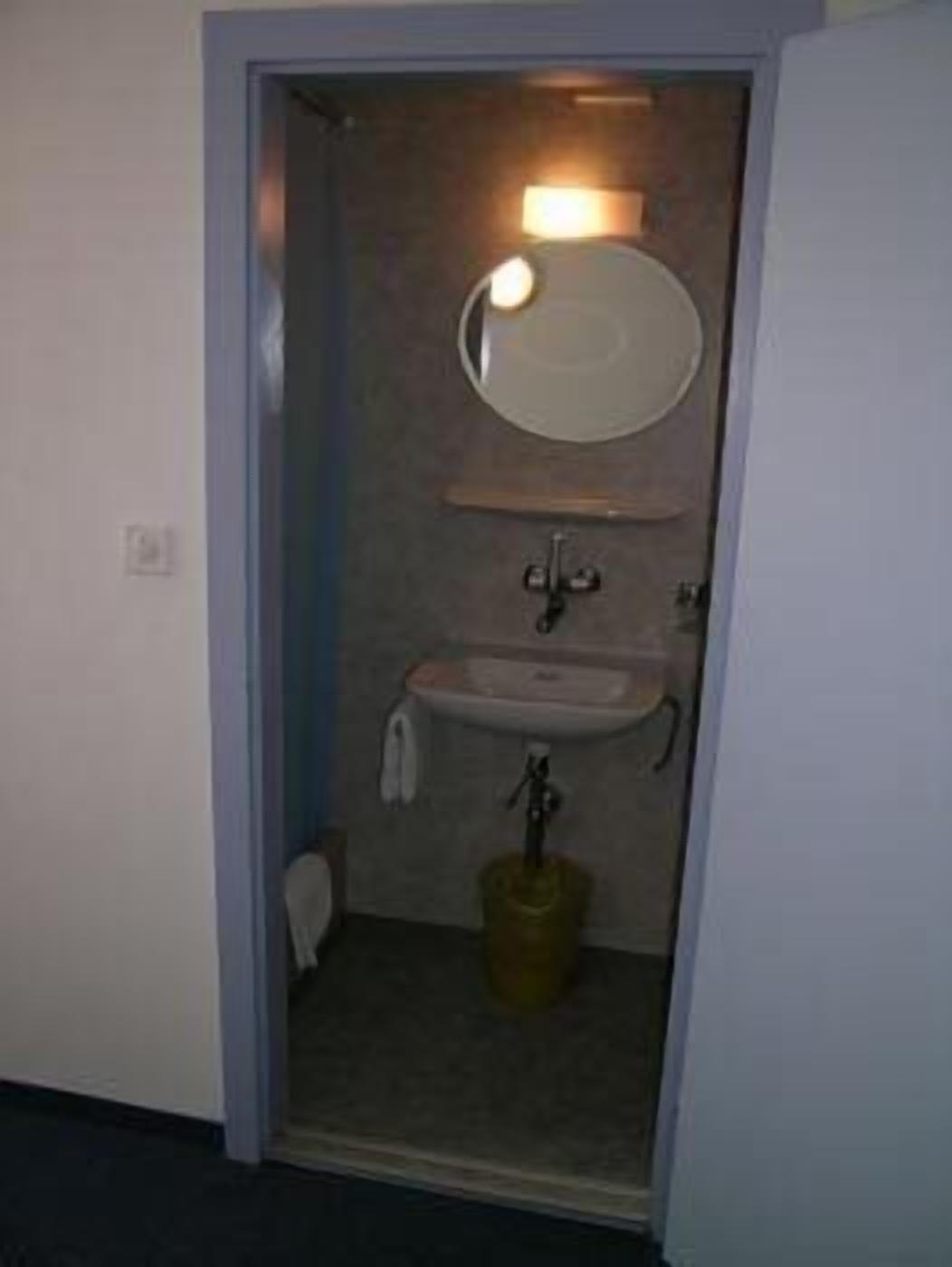 Un baño pequeño con lavamanos, espejo y toallero.