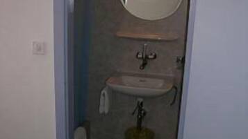 Un baño pequeño con lavamanos, espejo y toallero.