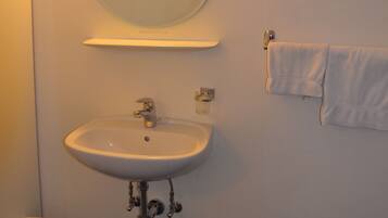 Ein Badezimmer mit Waschbecken, Spiegel, Handtuchhalter und Mülleimer.